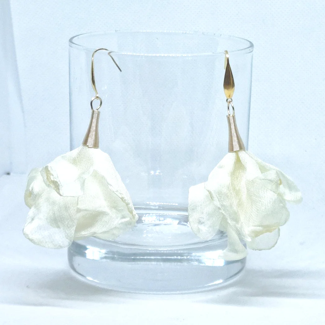 pendientes flor de seda color crudo colgados de un vaso