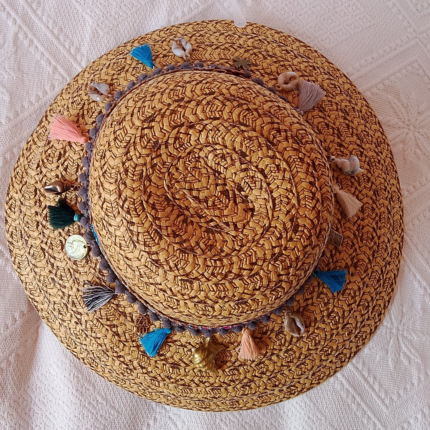 Sombrero de rafia color camel adornado con cintas , borlas y dijes, visto desde arriba