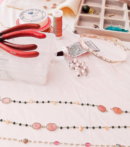 mesa de taller de bisutería con piezas, collares, pegamento y alicates