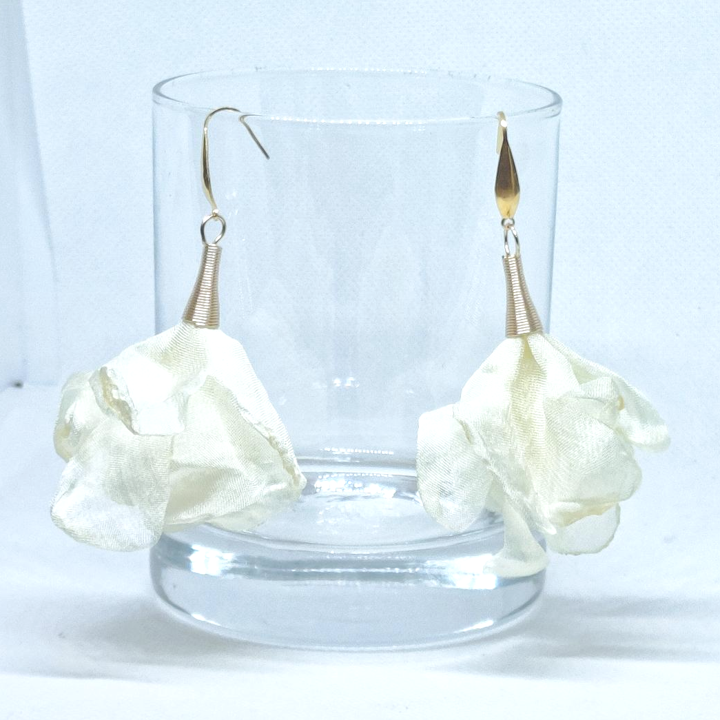 pendientes flor de seda color crudo colgados de un vaso