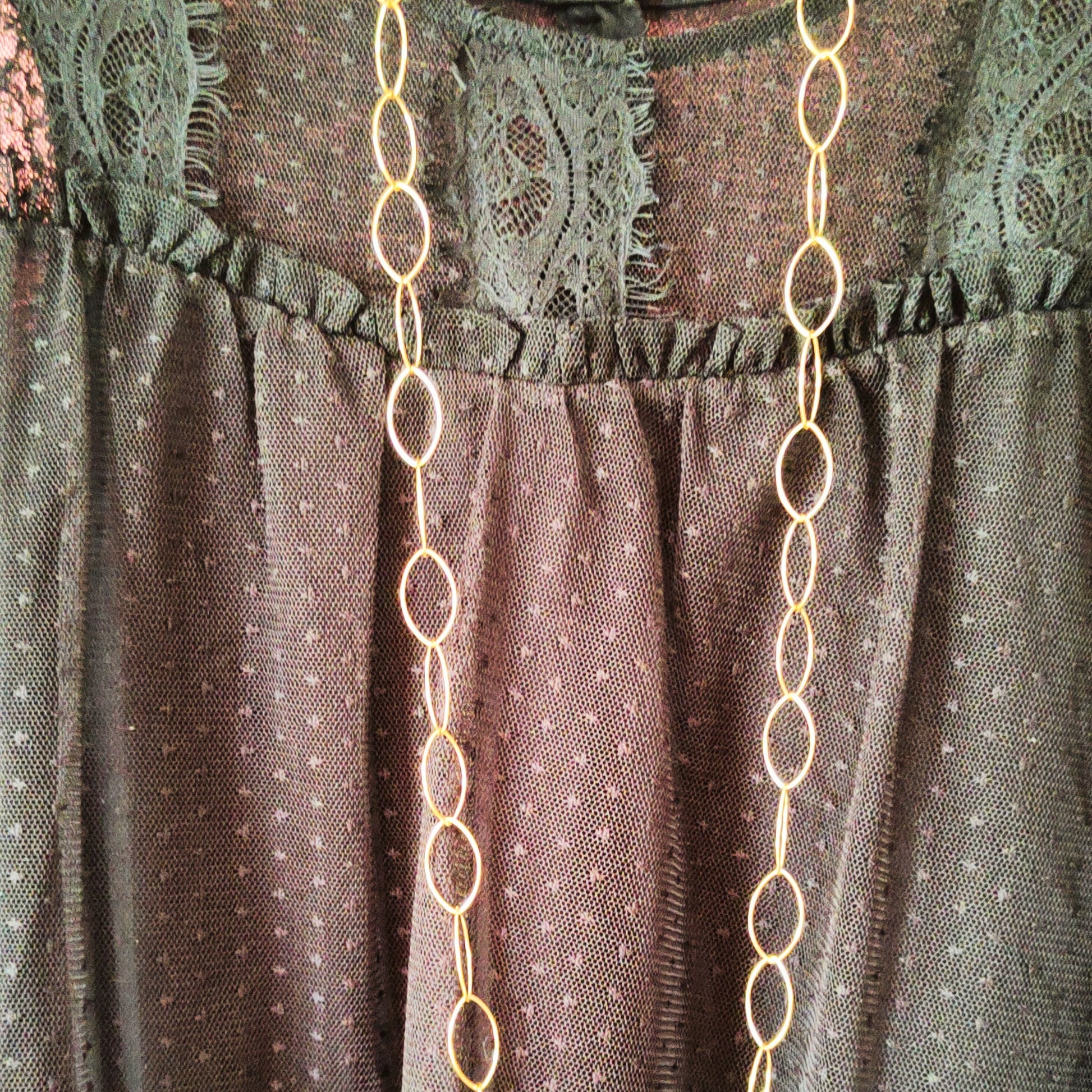 collar largo eslabones dorados puesto en blusa de encaje negra