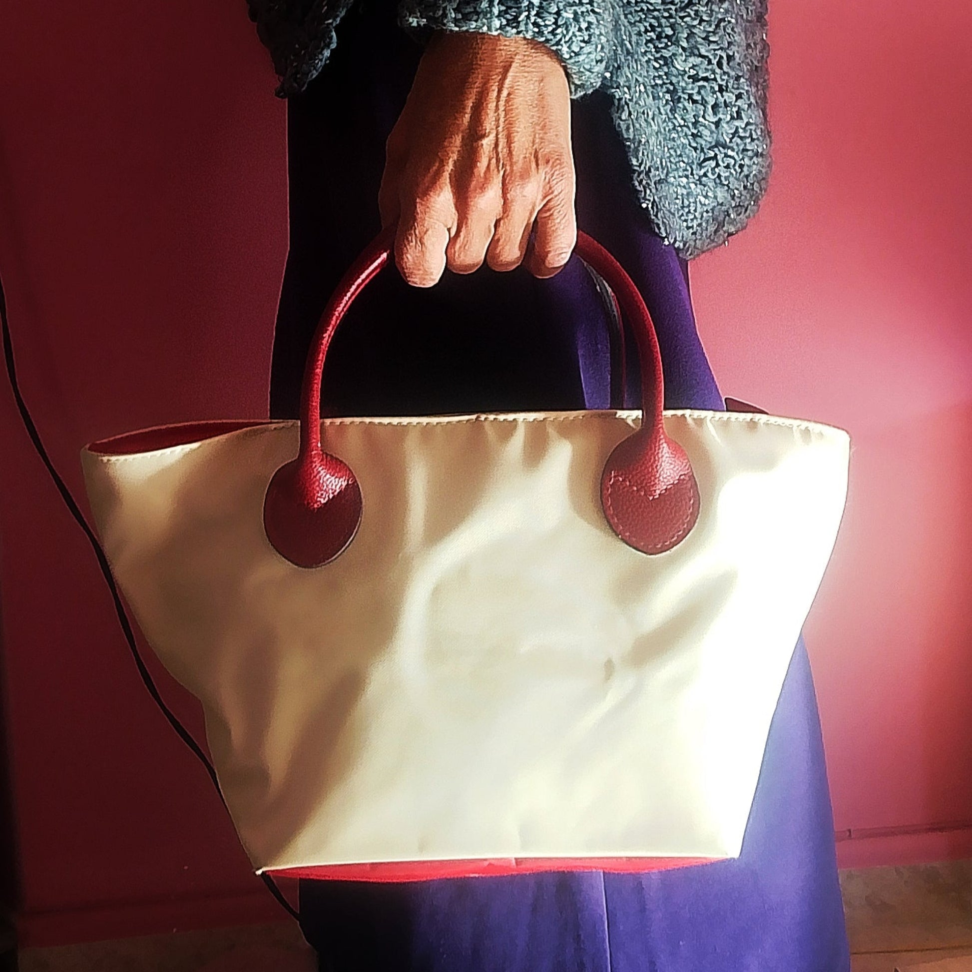 Bolso de loneta crudo y asas rojo oscuro de la mano mujer