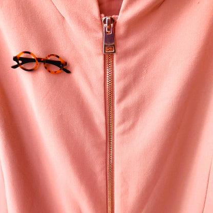 Broche gafas pasta  redondas con tonos marrones y beiges  puesto en cazadora rosa