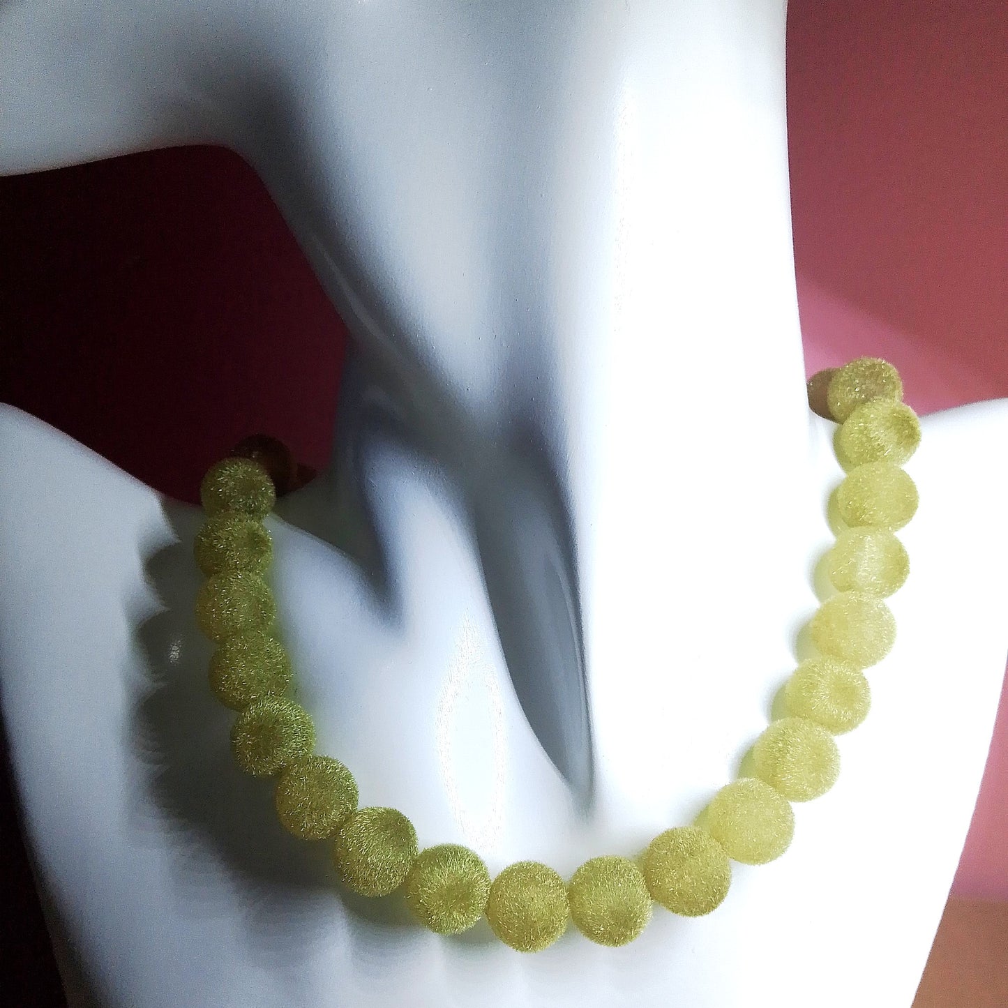 Collar de bolas verdes visto en busto blanco