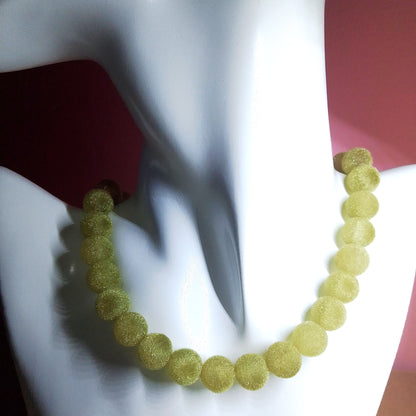 Collar de bolas verdes visto en busto blanco