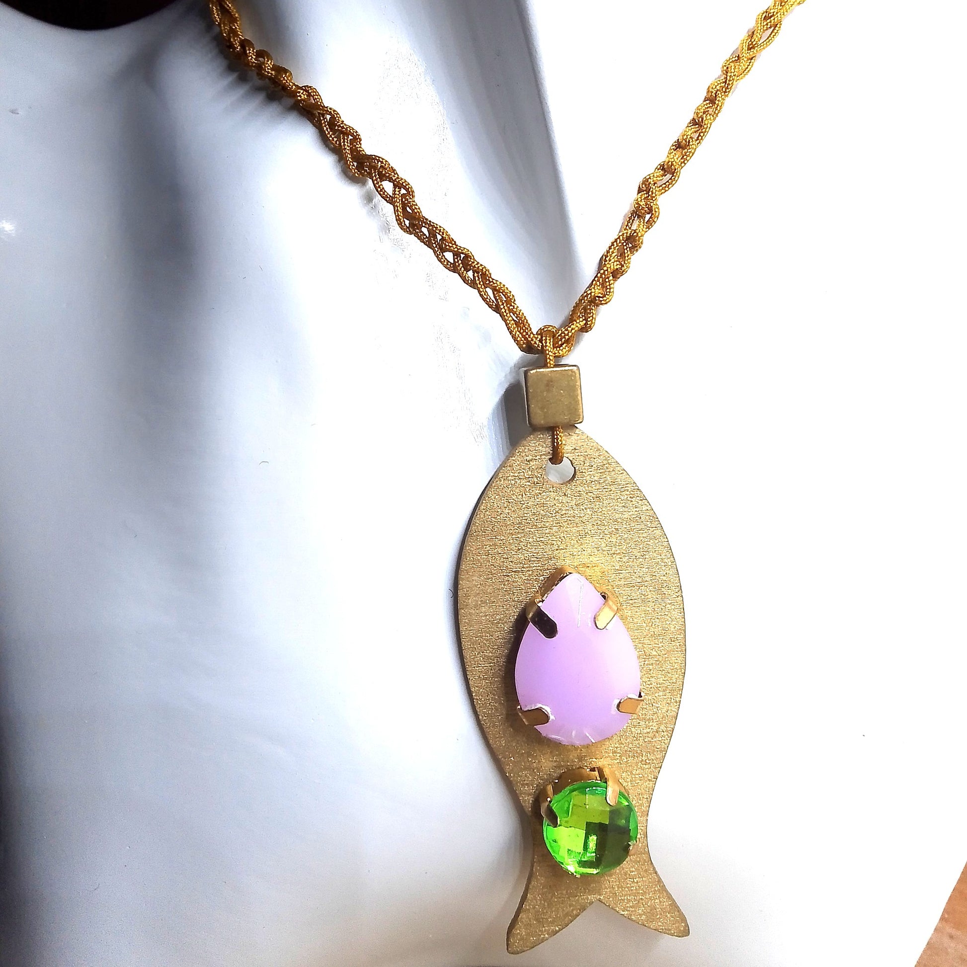 Pieza de collar en forma de pez de color dorado con piedras de bisutería con piedra lila y verde