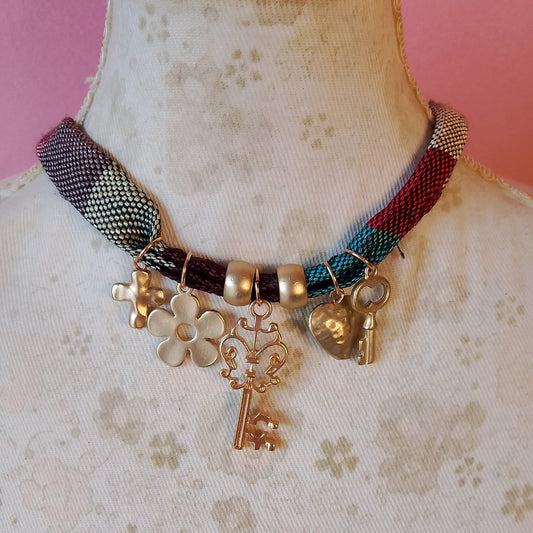 collar de tela con colgantes dorados cruz, flor, llave, corazon y llave pequeña