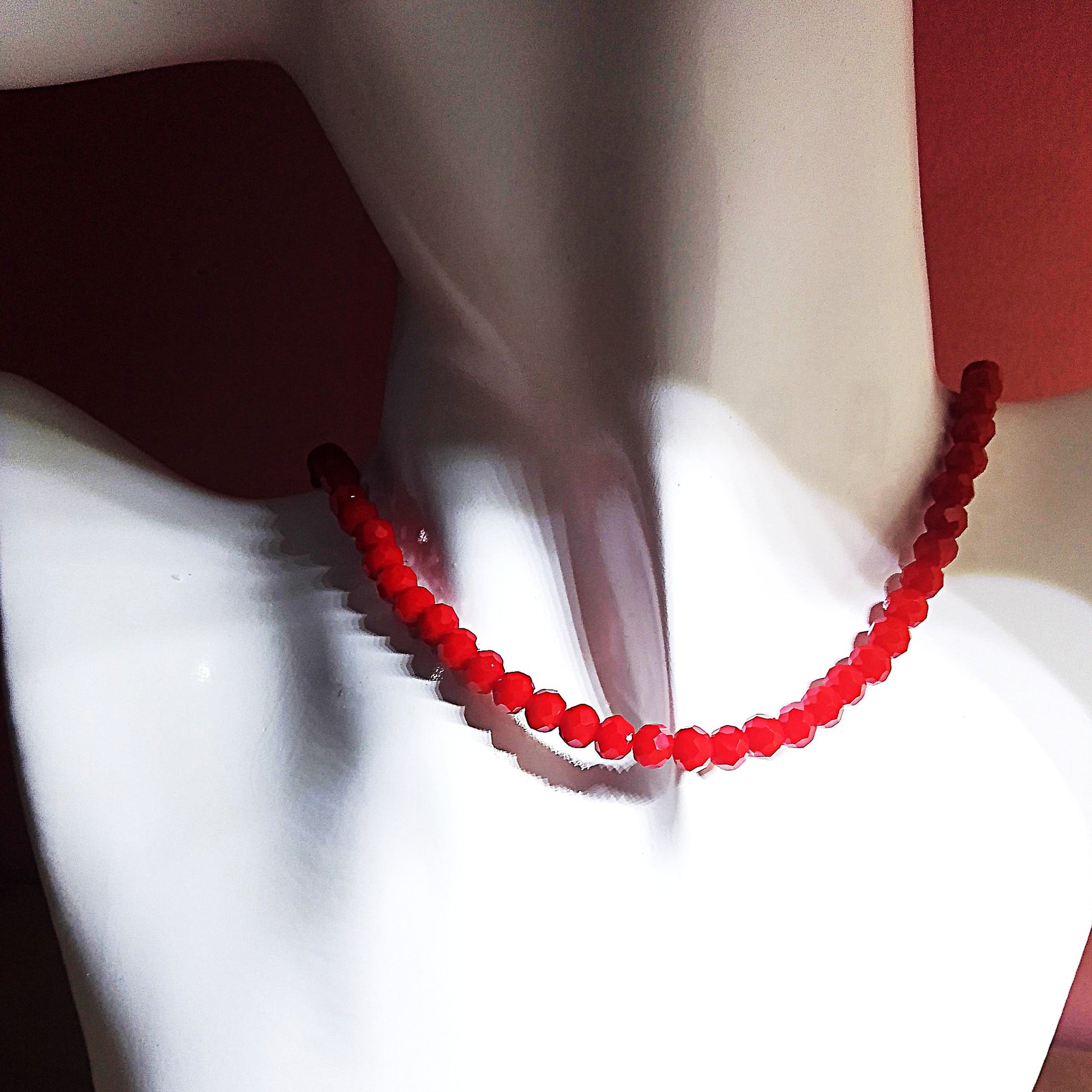 Collar de bolas facetadas en rojo en busto blanco