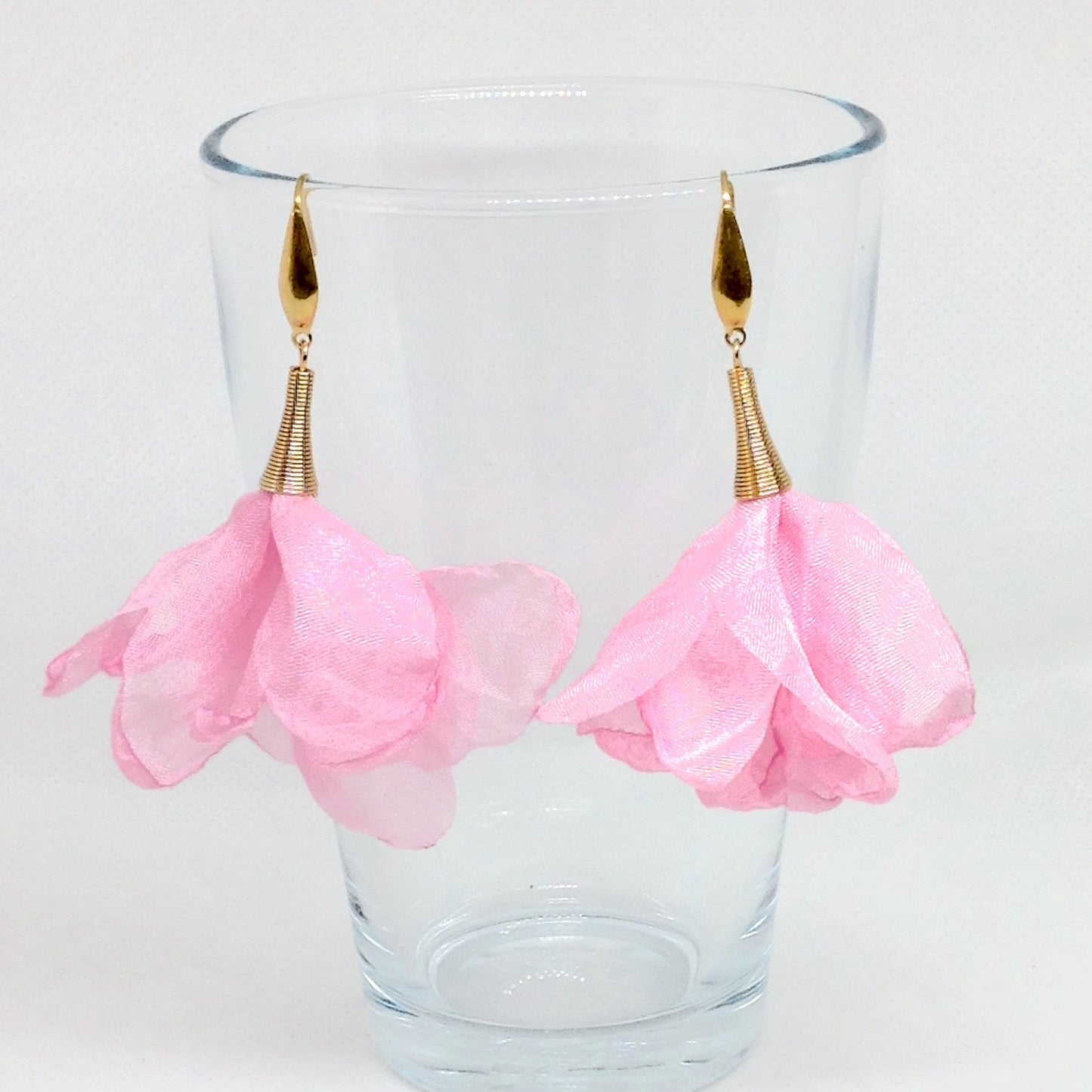 Pendientes flor de seda rosa colgados en vaso de cristal