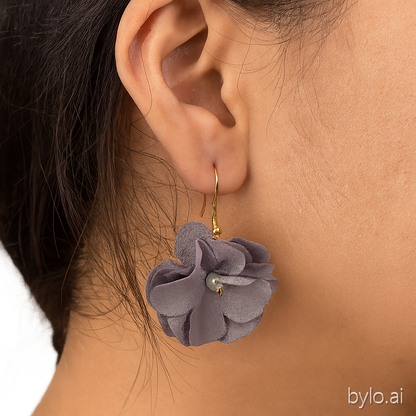 pendientes de flor de tela gris con gancho dorado y perla en el centro , puestos en mujer