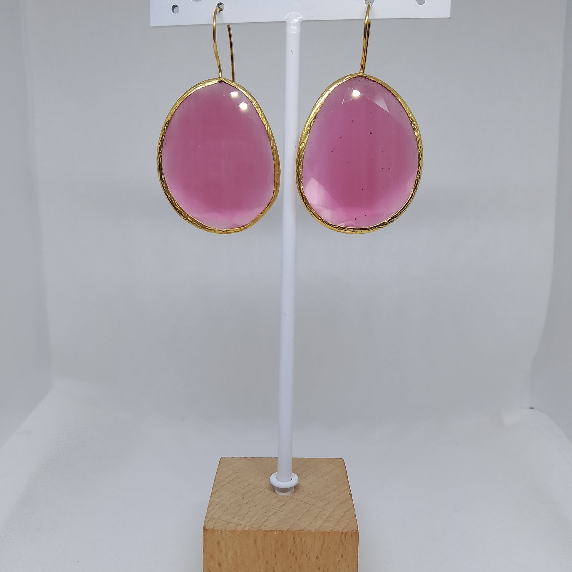 pendientes mineral rosa enmarcados en dorado y gancho , colgados en expositor