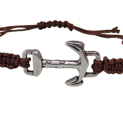 Pulsera náutica de macramé marrón con ancla metálica plateada, vista de cerca.