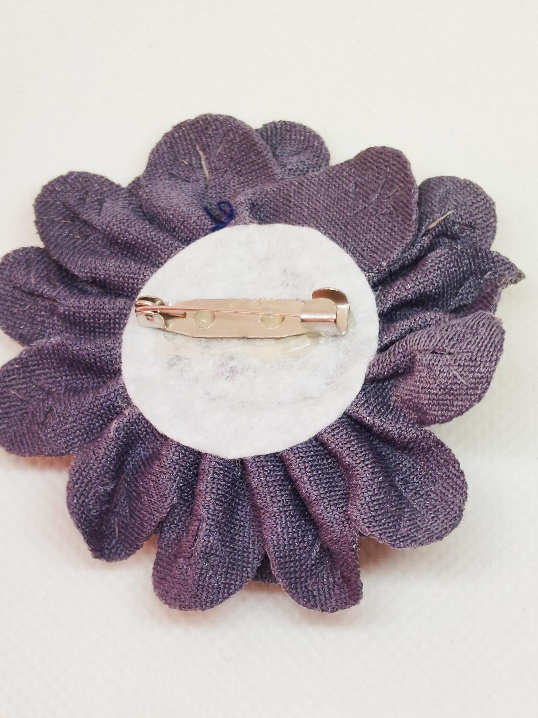 Broche flor de tela gris mostrando la aguja